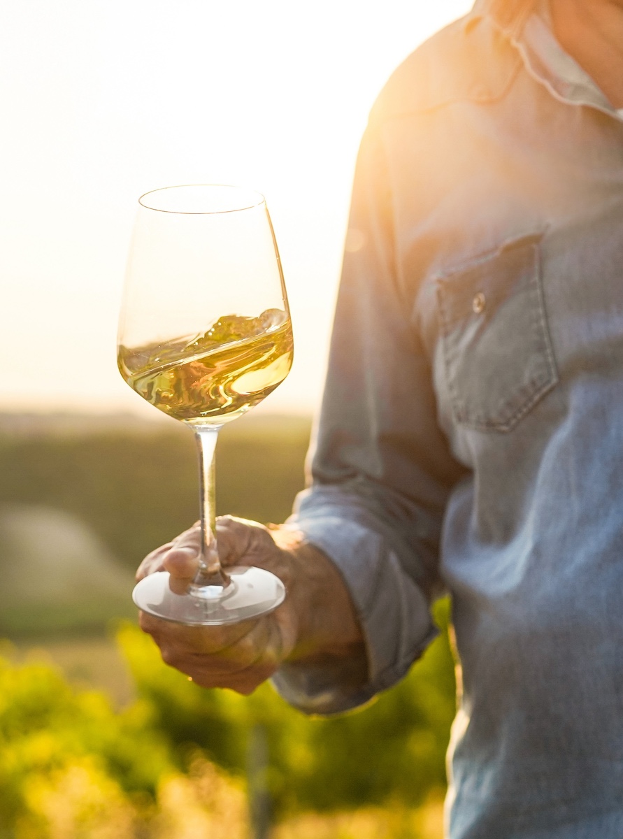 Man swirling white wine at sunset