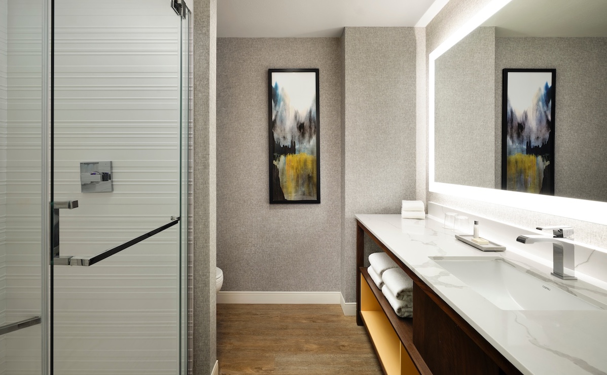 Bathroom with long vanity, walk-in shower and painting.