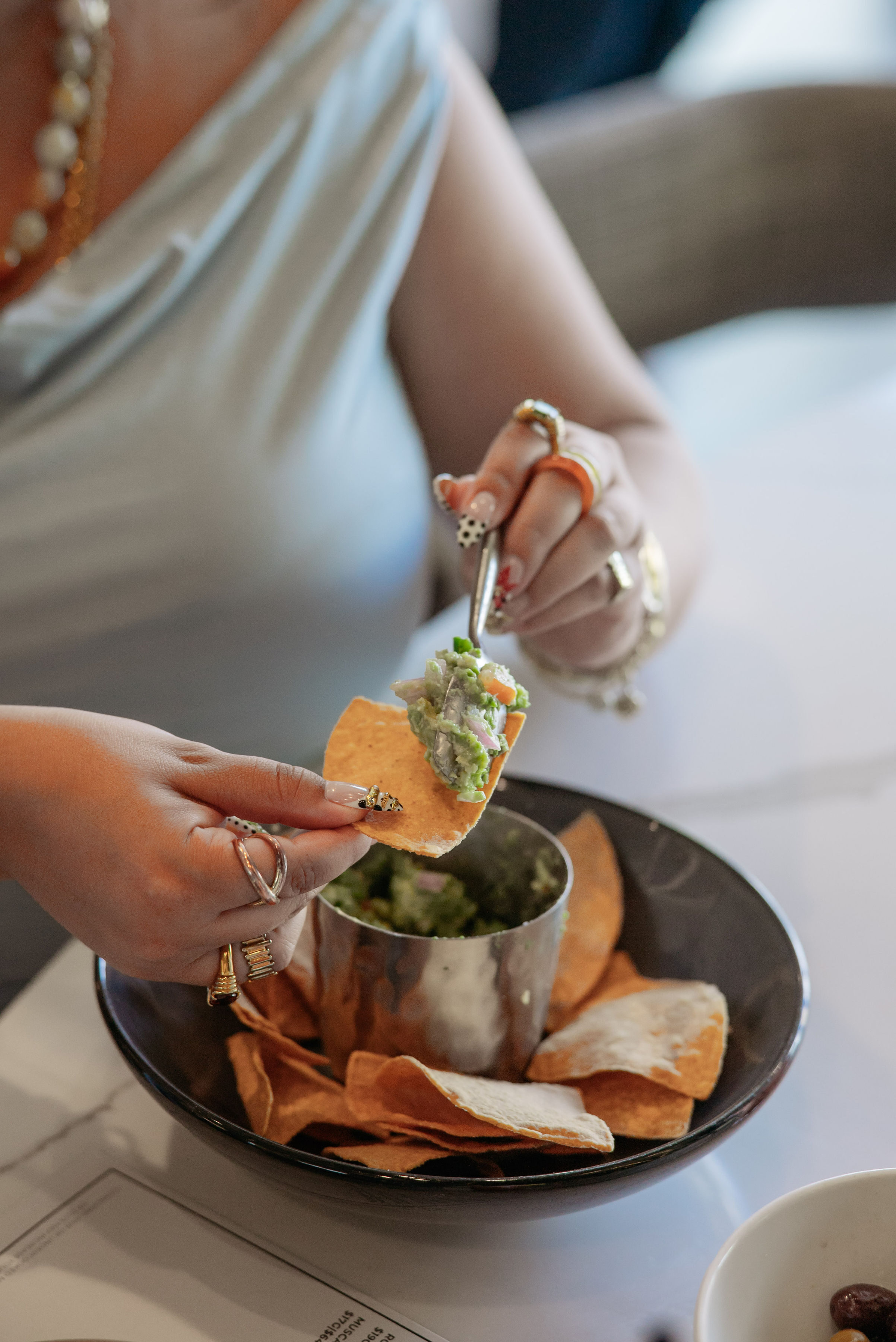 Diner spooning chunky guacamole onto a tortilla chip from a bowl of chips at Overland Kitchen & Tap